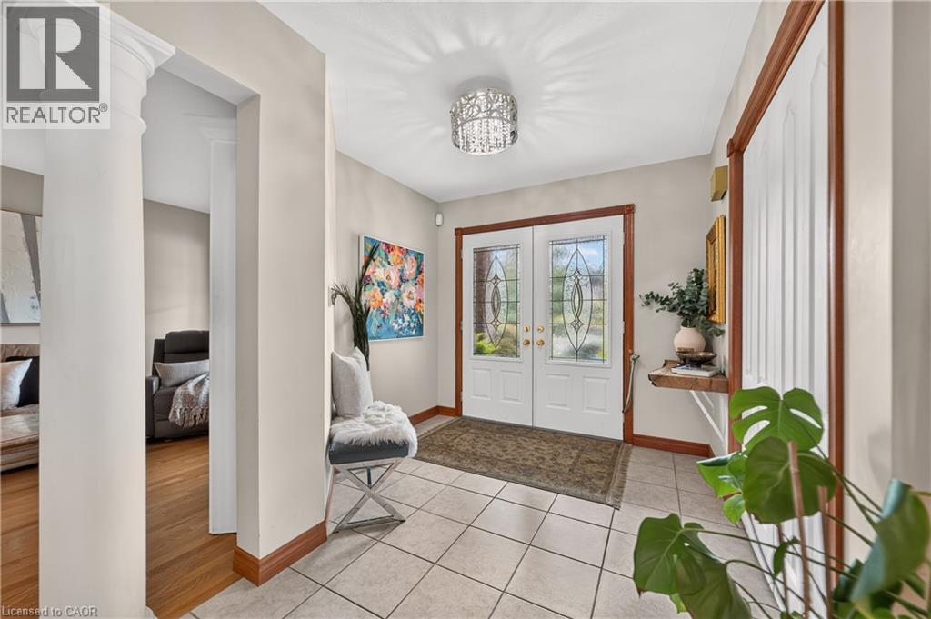 White double entry doors with leaded glass inserts, tiled flooring, decorative ceiling-mounted light fixture, and a structural column - 52 Archwood Crescent, Cambridge, ON