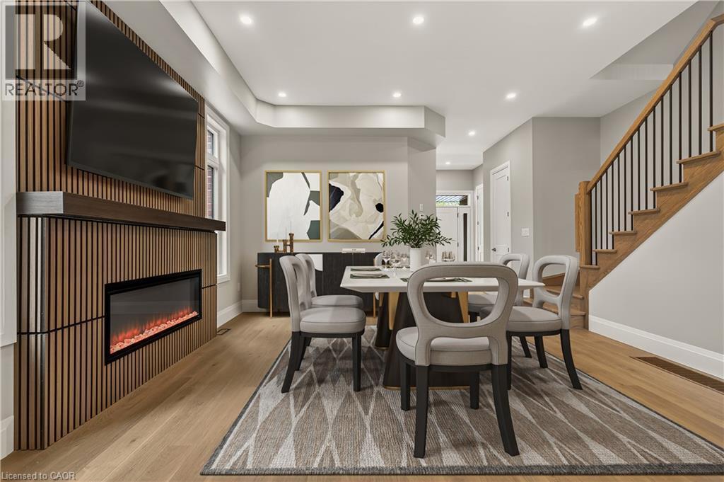Wood-finish flooring, recessed lighting, built-in electric fireplace, wood-slat feature wall, and a staircase with wood treads and black metal balusters - 279 Hess Street S, Hamilton, ON