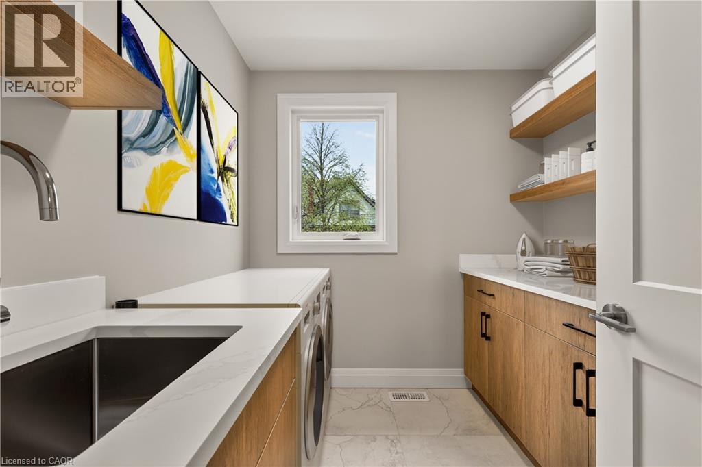 Laundry area with wood-finish cabinetry, white countertops, and a stainless steel sink - 279 Hess Street S, Hamilton, ON