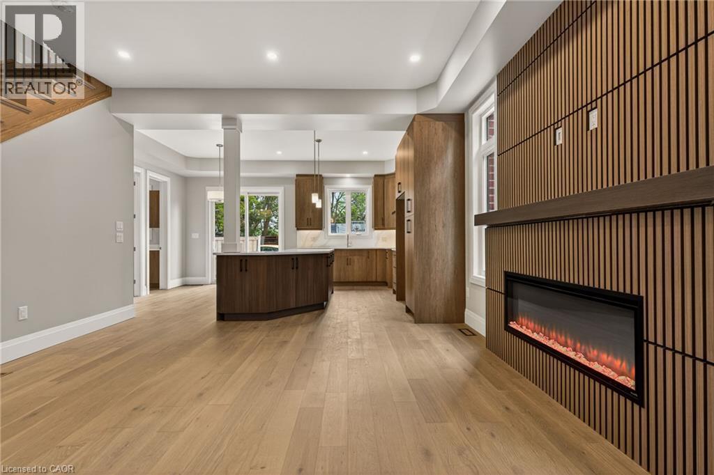 Light wood-finish flooring, recessed lighting, and a linear electric fireplace - 279 Hess Street S, Hamilton, ON