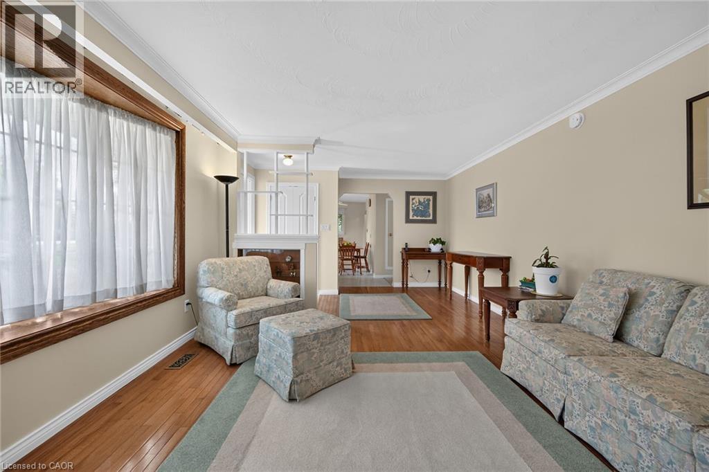 Hardwood flooring throughout, featuring a large window with wood trim, crown molding, and neutral wall tones - 799 Highway 6, Caledonia, ON