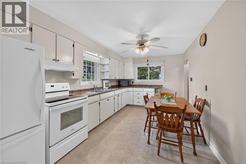 Kitchen featuring white cabinetry, a complete set of white appliances, and a ceiling fan with integrated lighting - 799 Highway 6, Caledonia, ON