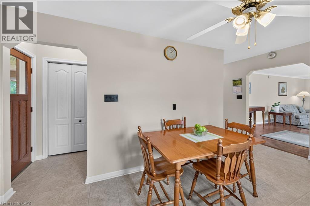 Tiled flooring, warm neutral wall tones, arched doorway, wood-panel entry door, and a ceiling fan with integrated lighting - 799 Highway 6, Caledonia, ON