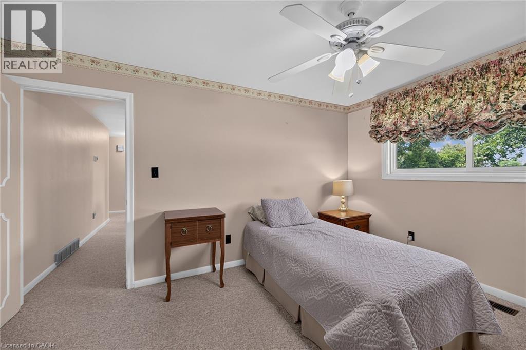 Neutral wall paint, ceiling fan, window with exterior foliage, and carpeted flooring - 799 Highway 6, Caledonia, ON