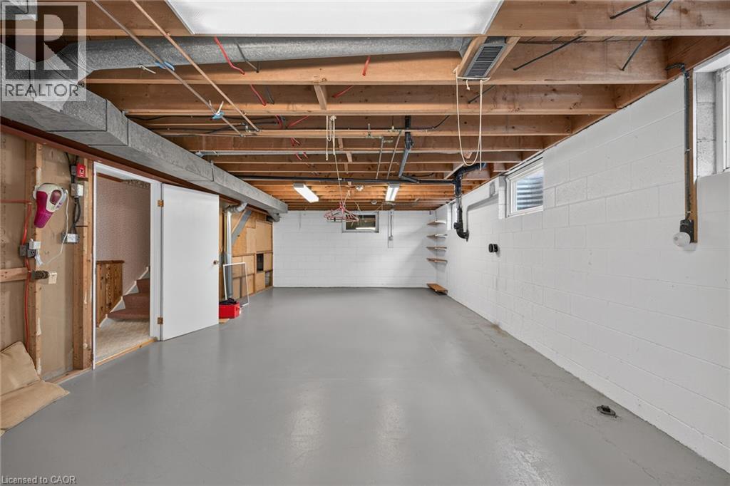 Finished concrete flooring, exposed ceiling joists, white painted block walls, and built-in shelving - 799 Highway 6, Caledonia, ON