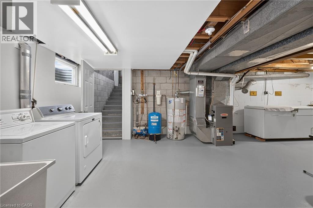 Concrete block walls with painted flooring, utility sink, and installed water heater - 799 Highway 6, Caledonia, ON
