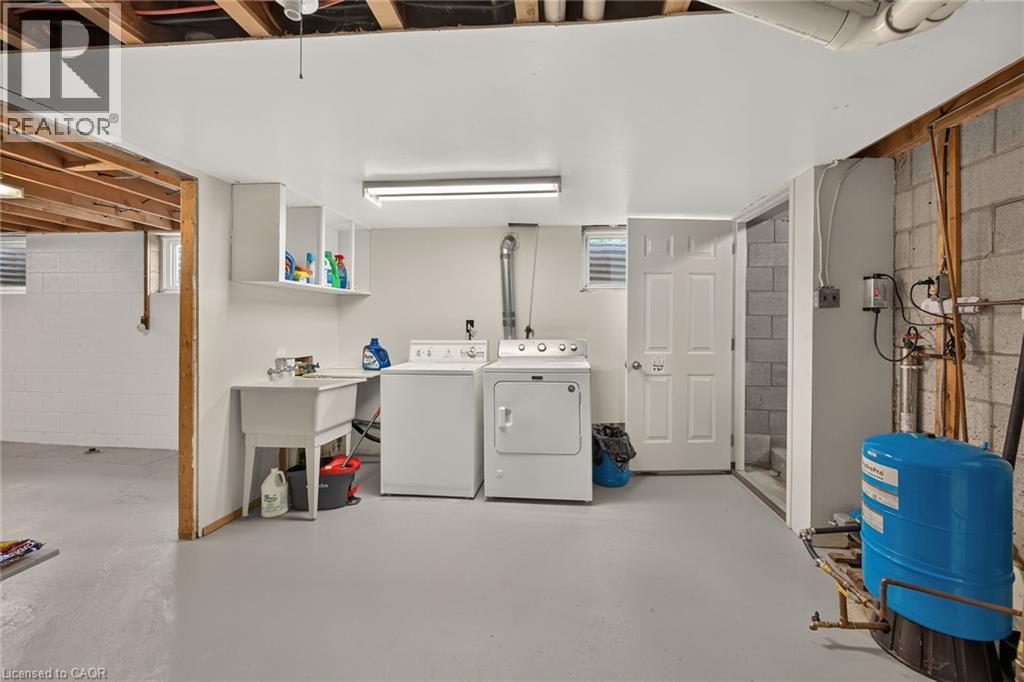 Laundry area featuring a utility sink, wall-mounted shelving, and appliances - 799 Highway 6, Caledonia, ON