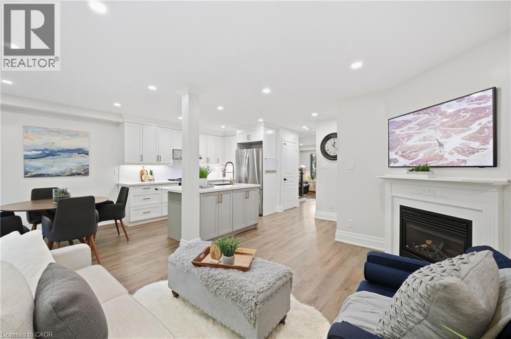 Open-concept living space featuring wood-finish flooring, recessed lighting, and a white fireplace mantel - 2409 Postmaster Drive, Oakville, ON