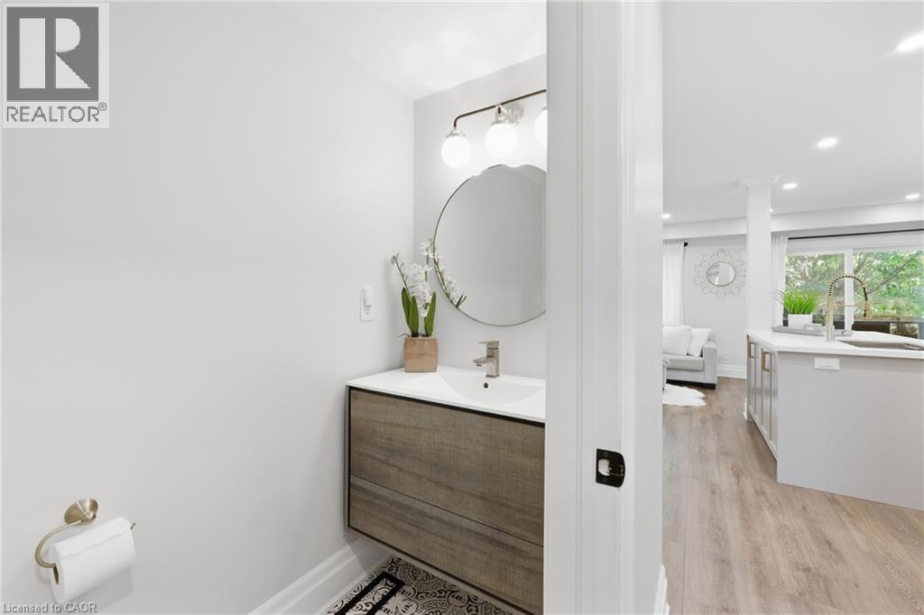 Floating vanity with wood-finish cabinetry, under-mount sink, and wall-mounted light fixture - 2409 Postmaster Drive, Oakville, ON