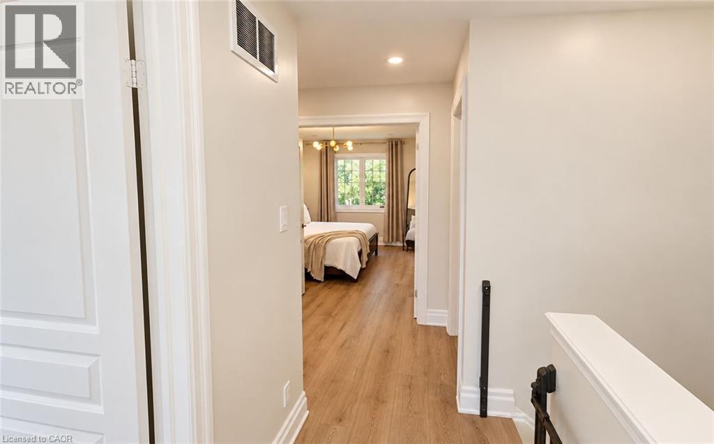 Hallway with light wood-finish flooring, white trim, and neutral wall paint - 2409 Postmaster Drive, Oakville, ON