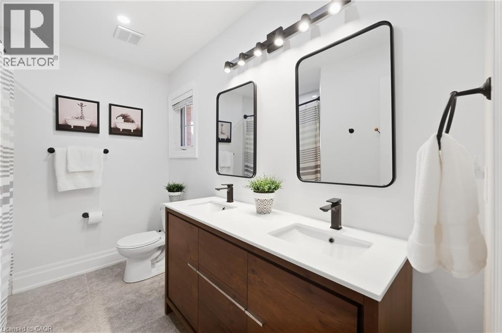 Dual vanity with integrated sinks, dark wood-finish cabinetry, matte black fixtures, and framed mirrors - 2409 Postmaster Drive, Oakville, ON