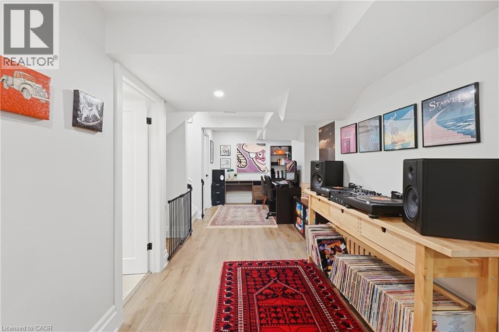 Wood-finish flooring throughout, white walls, recessed lighting, and a partial black metal railing - 2409 Postmaster Drive, Oakville, ON