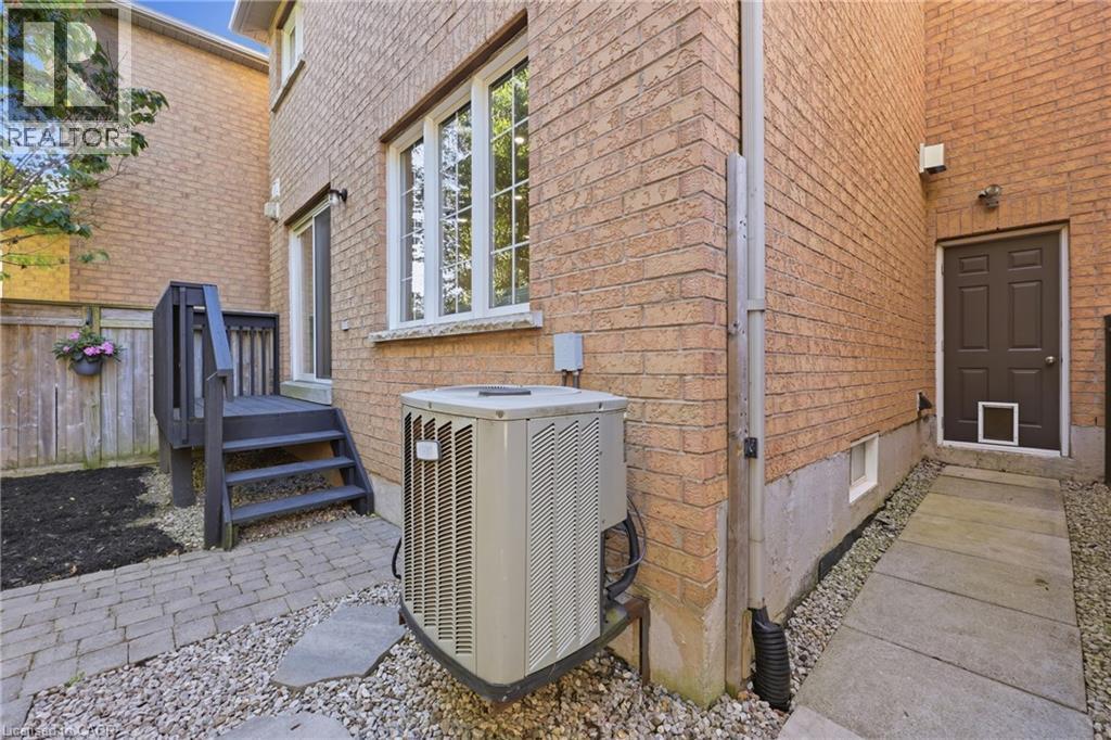 Brick exterior with a dark-stained wood deck, white-framed windows, and a paver stone patio - 2409 Postmaster Drive, Oakville, ON
