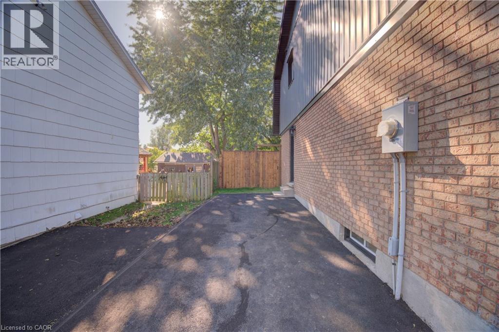 Brick exterior with a utility meter, a finished basement window, and an asphalt driveway - 210 Ferguson Avenue, Cambridge, ON