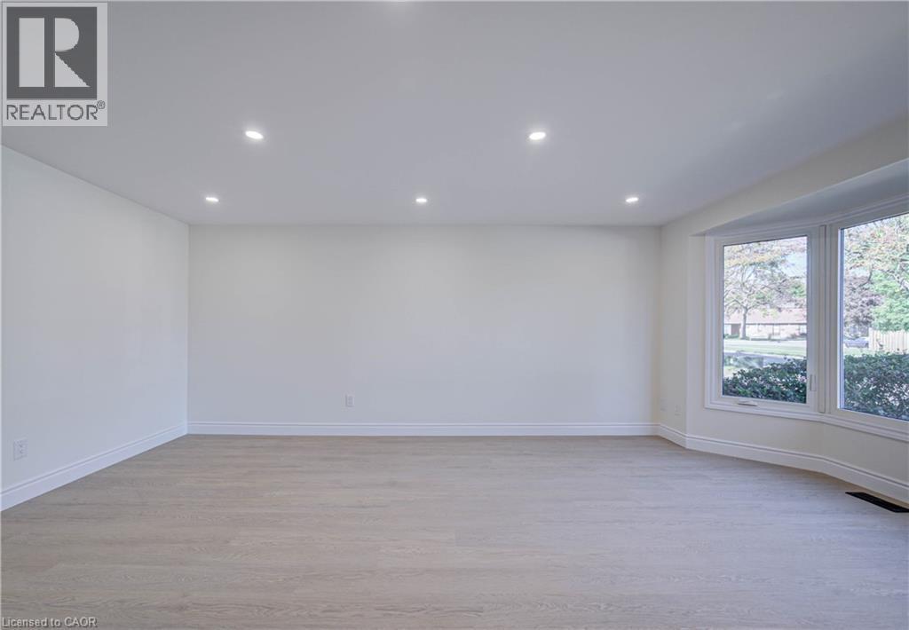 Expansive room featuring wood-finish flooring, recessed lighting, and a prominent bay window - 210 Ferguson Avenue, Cambridge, ON