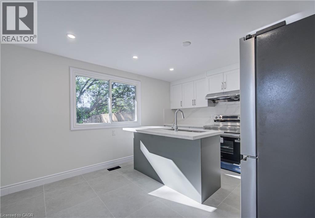 Kitchen featuring white upper cabinetry, stainless steel appliances, a center island with a sink, and recessed lighting - 210 Ferguson Avenue, Cambridge, ON
