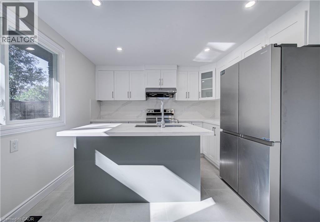 White shaker cabinetry, stainless steel appliances, central island with seating, recessed lighting, and tile flooring - 210 Ferguson Avenue, Cambridge, ON