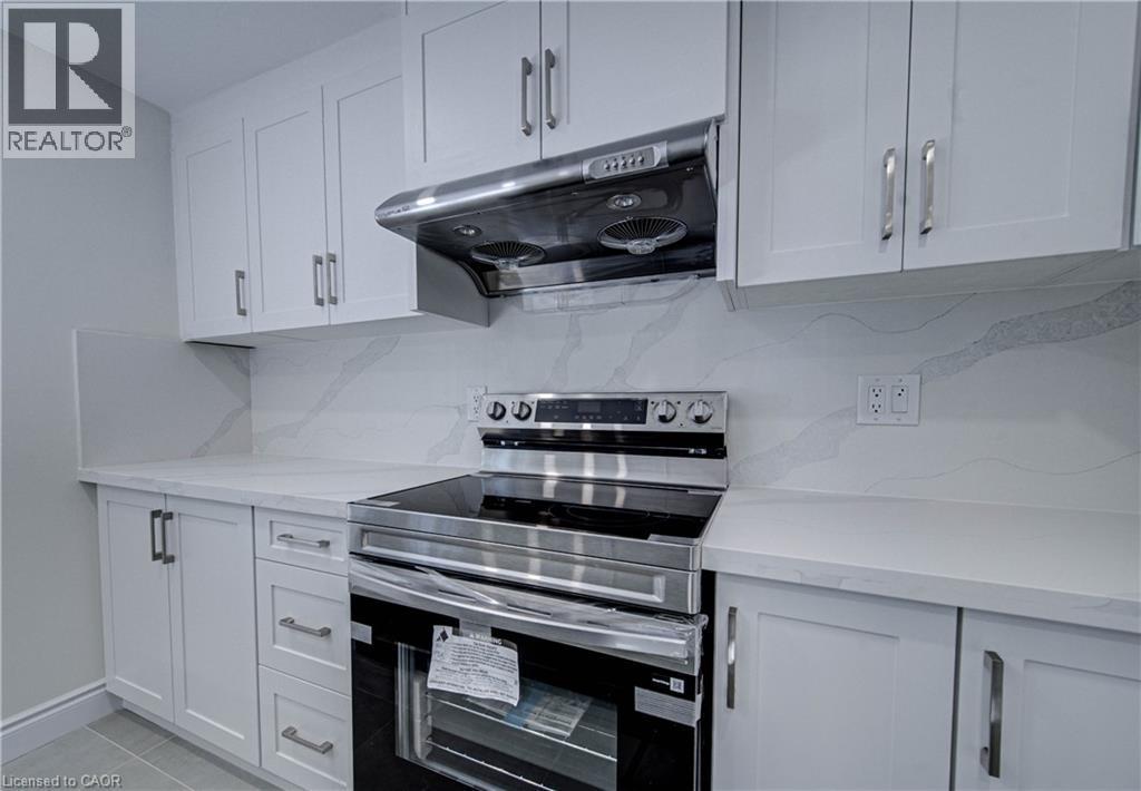 White shaker cabinetry, stainless steel range hood, electric range, light-toned countertops, and a patterned backsplash - 210 Ferguson Avenue, Cambridge, ON