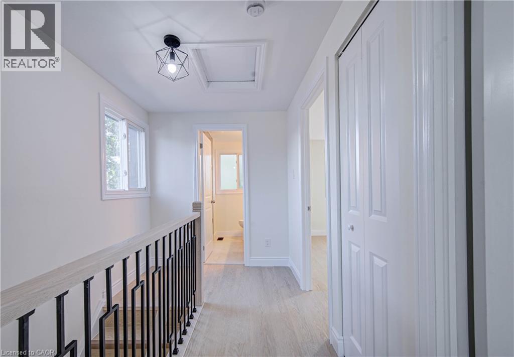 Light wood-finish flooring, white walls, and a modern geometric ceiling light fixture - 210 Ferguson Avenue, Cambridge, ON
