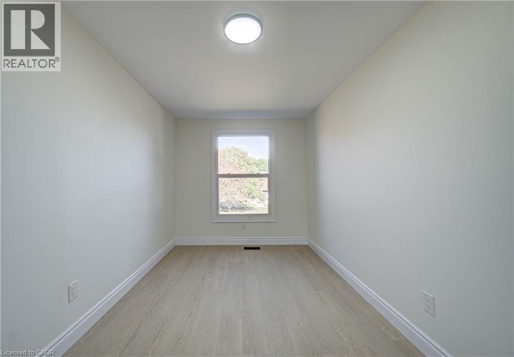 Bright room featuring light-toned wood-finish flooring, a single window, and a flush-mount ceiling light - 210 Ferguson Avenue, Cambridge, ON