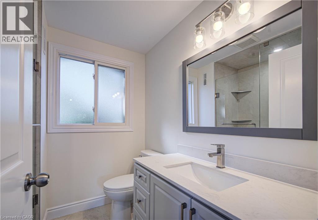 Frosted window, sleek vanity with integrated sink, contemporary vanity lighting, frameless mirror, and modern brushed nickel faucet - 210 Ferguson Avenue, Cambridge, ON