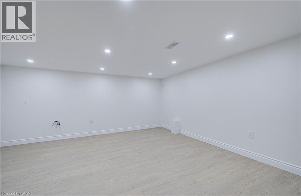 Recessed lighting illuminates the open area with light wood-finish flooring and white walls - 210 Ferguson Avenue, Cambridge, ON