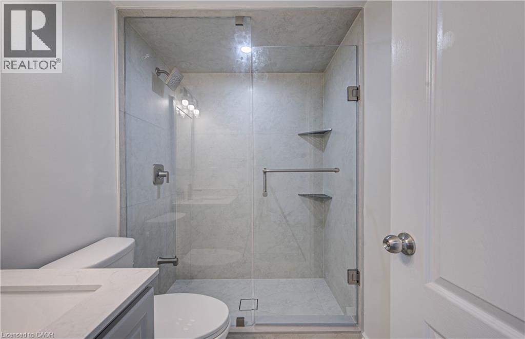 Glass-enclosed shower with tiled walls and floor, featuring a multi-function showerhead and built-in shelving - 210 Ferguson Avenue, Cambridge, ON