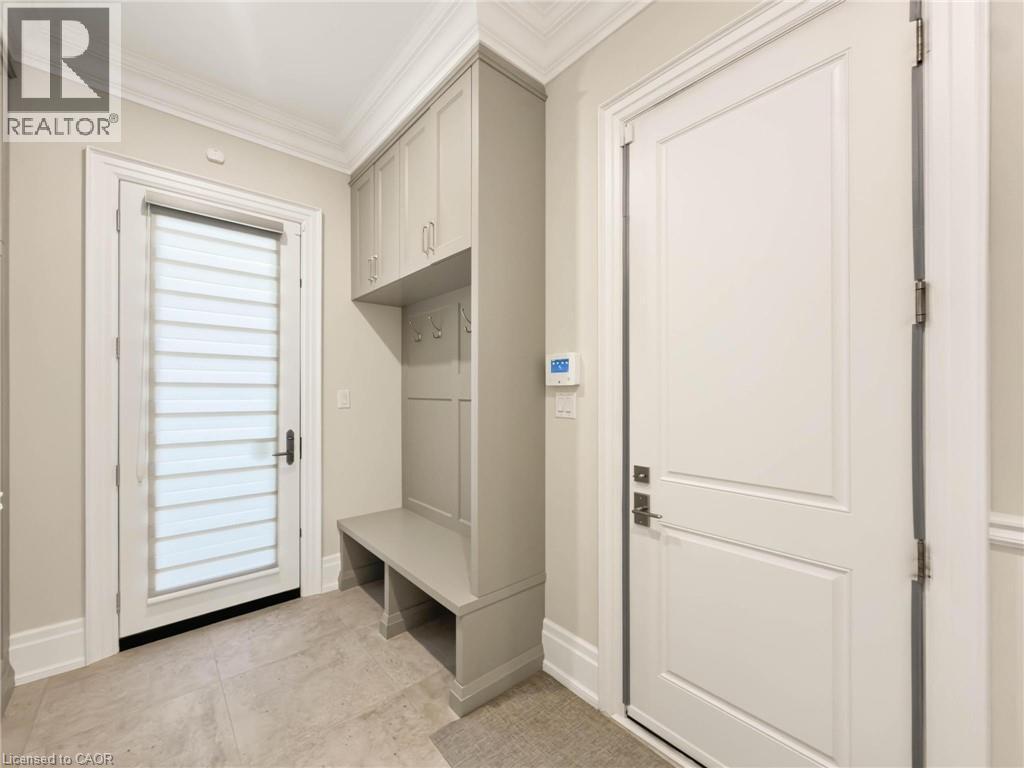Built-in cabinetry with bench seating and storage, tiled flooring, crown molding, and a paneled interior door - 236 Poplar Drive, Burlington, ON