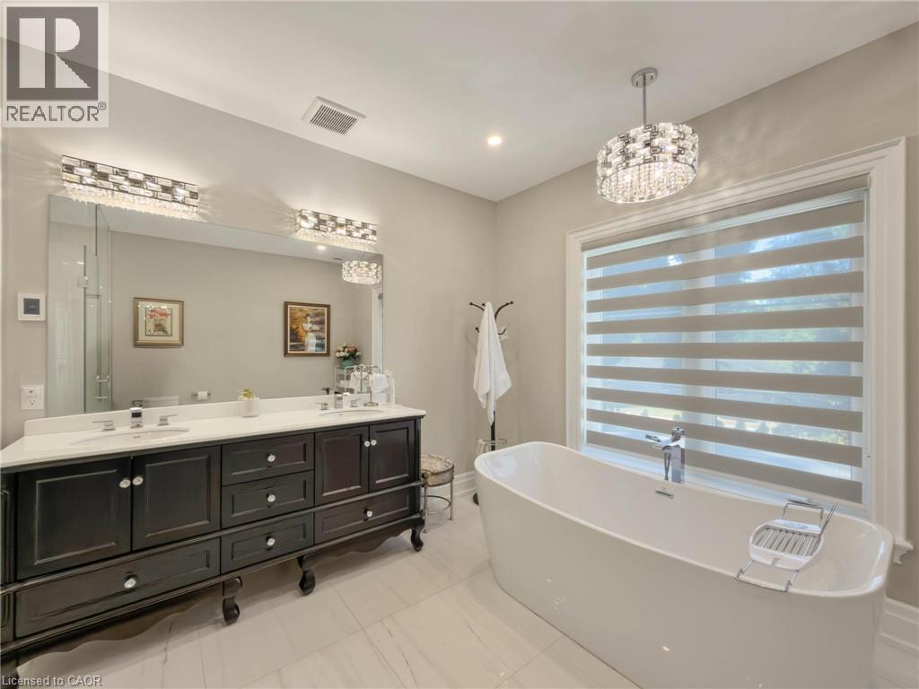 Freestanding soaking tub, dual vanity with undermount sinks, large wall mirror, crystal vanity lighting, and a crystal chandelier - 236 Poplar Drive, Burlington, ON