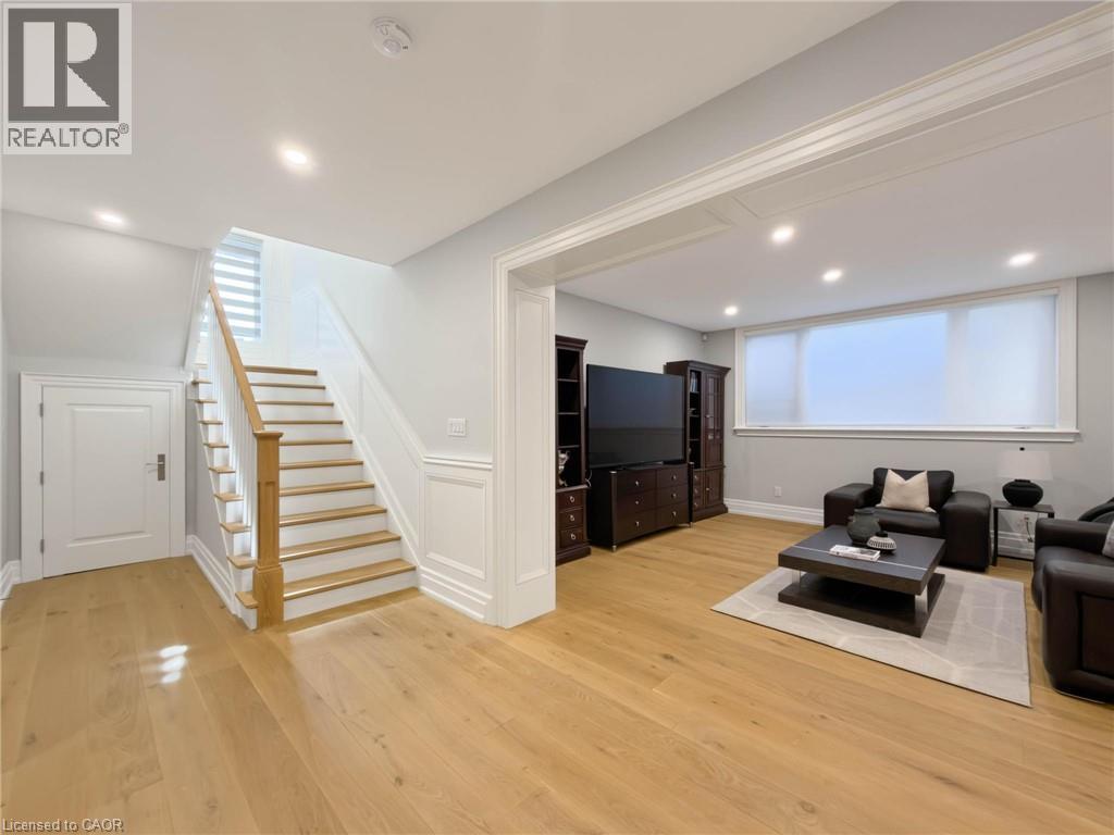 Hardwood flooring, recessed lighting, white wainscoting, white trim, and a large window with roller shades - 236 Poplar Drive, Burlington, ON