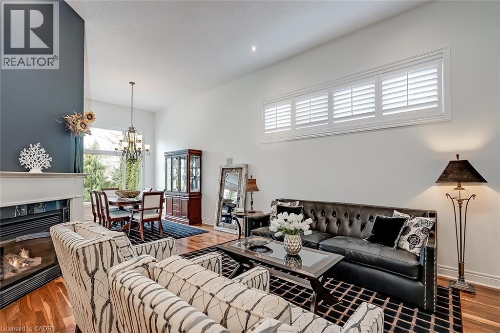 Hardwood flooring, high ceilings, fireplace with mantel, transom windows with white shutters, and a chandelier - 4285 Couples Crescent, Burlington, ON
