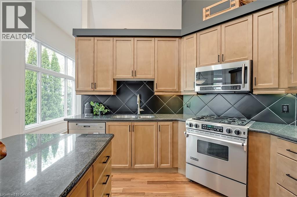 Wood-finish cabinetry complemented by dark countertops, stainless steel appliances, and a diagonal tile backsplash - 4285 Couples Crescent, Burlington, ON