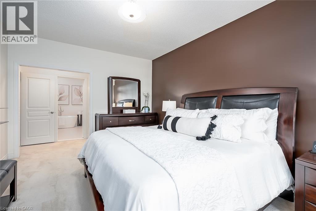 Light-colored carpeting, dark accent wall, recessed ceiling light, and a wood-finish bed frame - 4285 Couples Crescent, Burlington, ON