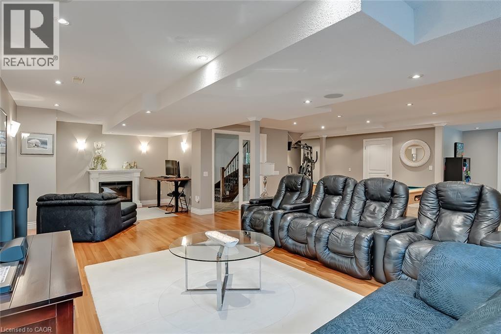 Recessed lighting, wood-finish flooring, white fireplace, built-in staircase, and wall sconces - 4285 Couples Crescent, Burlington, ON