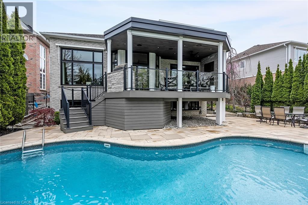 Swimming pool with a curved edge and surrounding paved patio - 4285 Couples Crescent, Burlington, ON