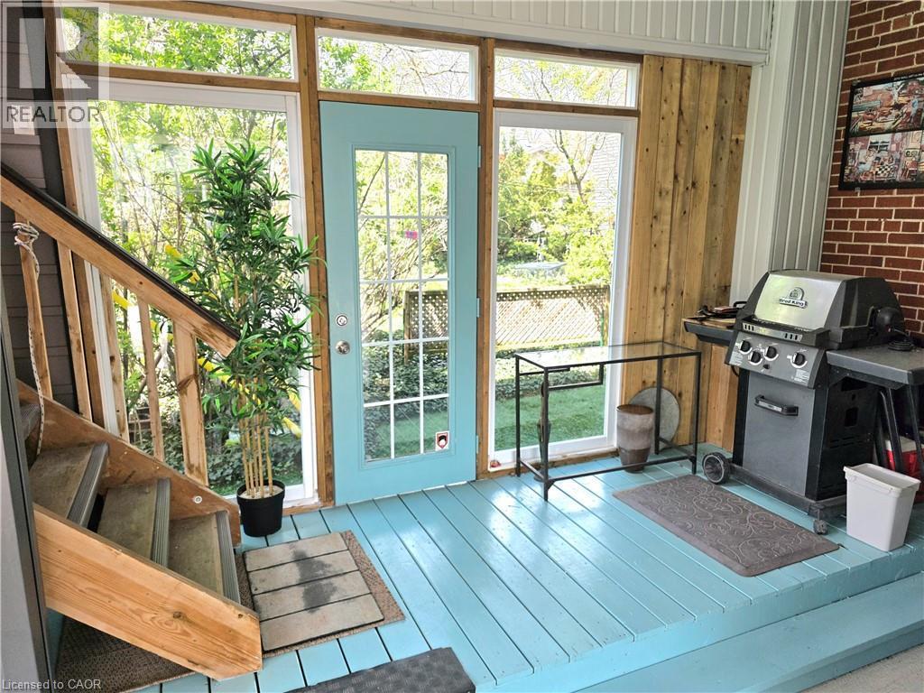 Enclosed patio featuring a wood floor, large windows, BBQ area and stairs to the studio - 16 Forest Hill Road, St. Catharines, ON