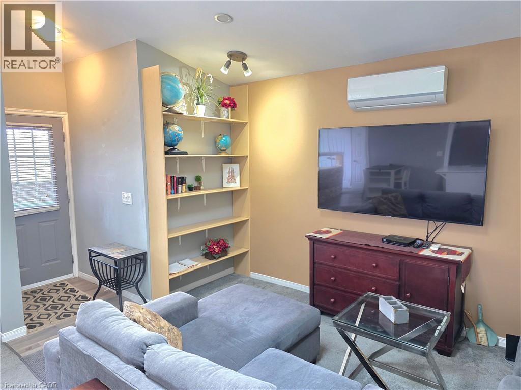 Living area featuring vinyl flooring, built-in shelving, lots of lighting and a wall-mounted air conditioning unit - 16 Forest Hill Road, St. Catharines, ON