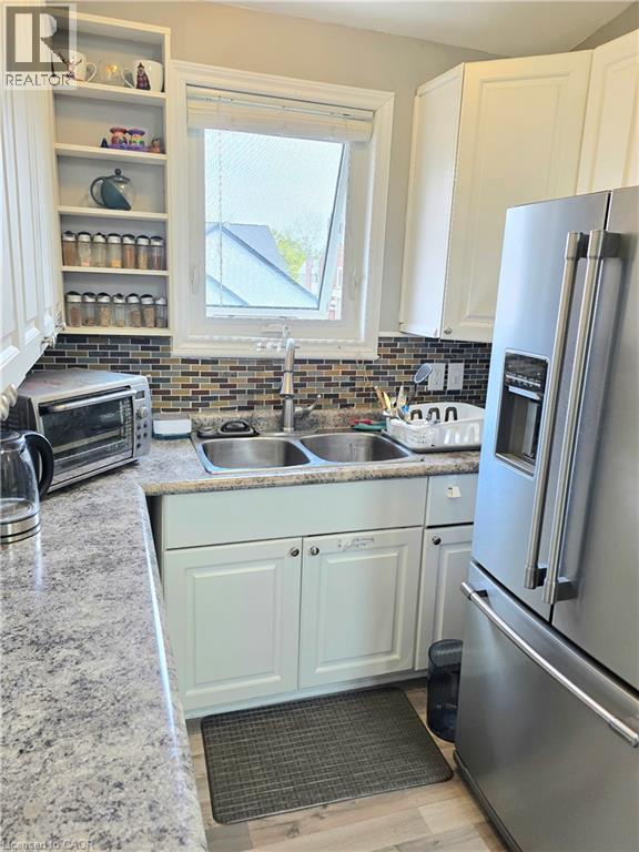 Kitchen featuring white cabinetry and a mosaic tile backsplash - 16 Forest Hill Road, St. Catharines, ON