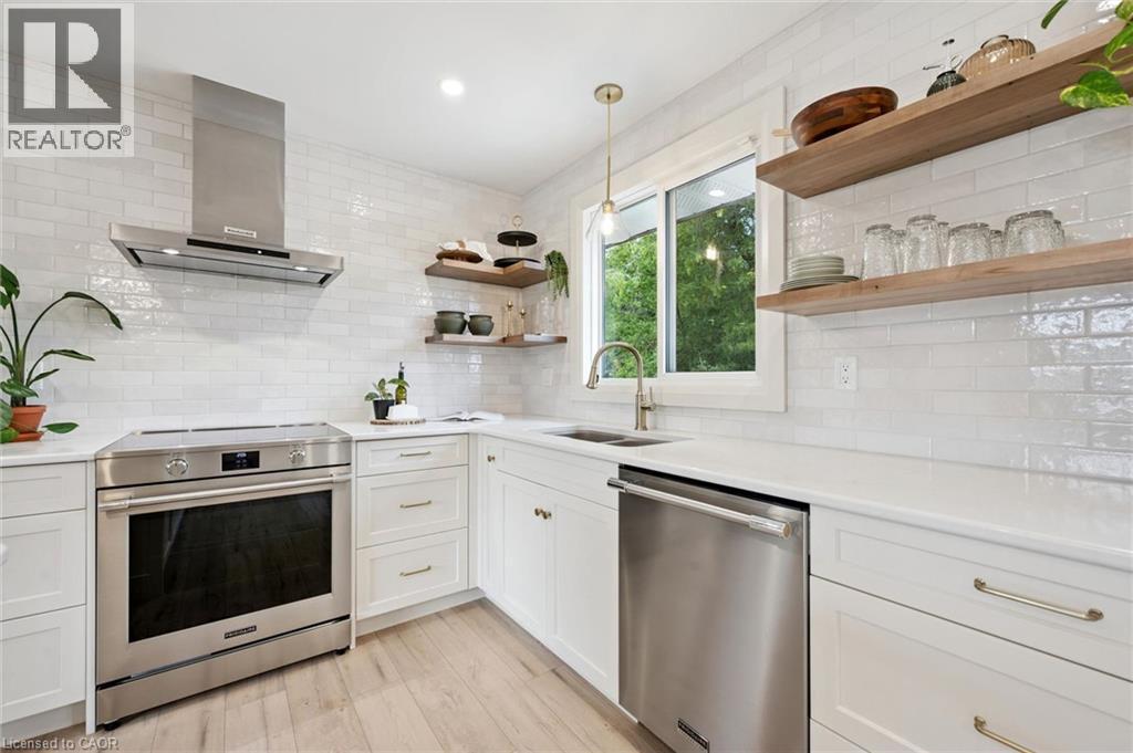 Modern kitchen featuring white shaker cabinets, stainless steel appliances, open shelving, and a subway tile backsplash - 8 Christian Street, Baden, ON