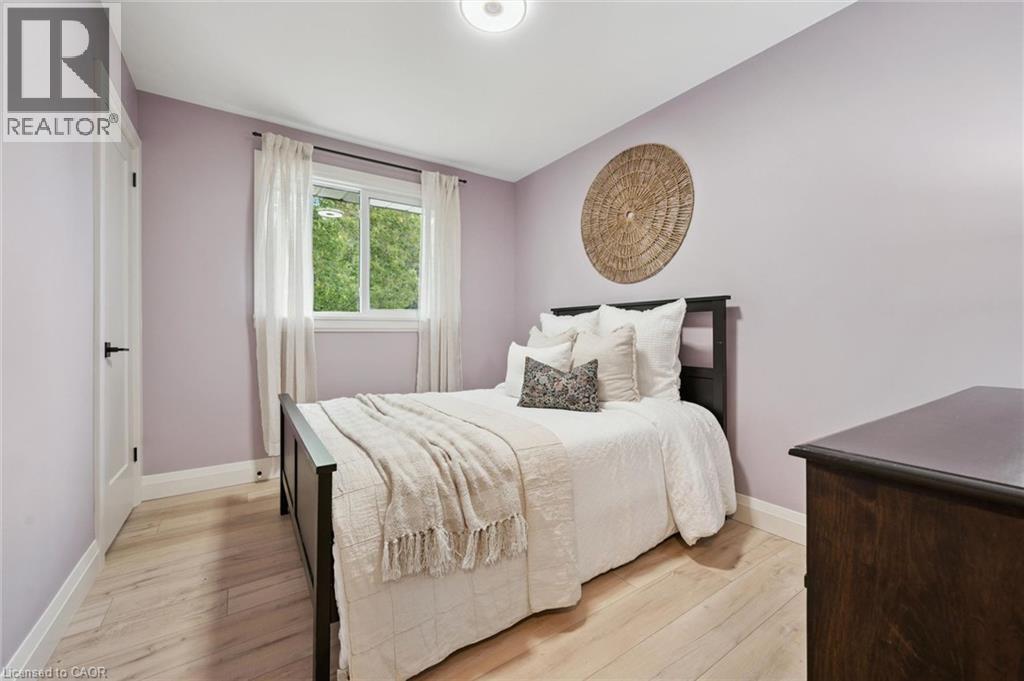 Light wood-finish flooring with white trim, a double-paned window, and an overhead flush-mount light fixture - 8 Christian Street, Baden, ON
