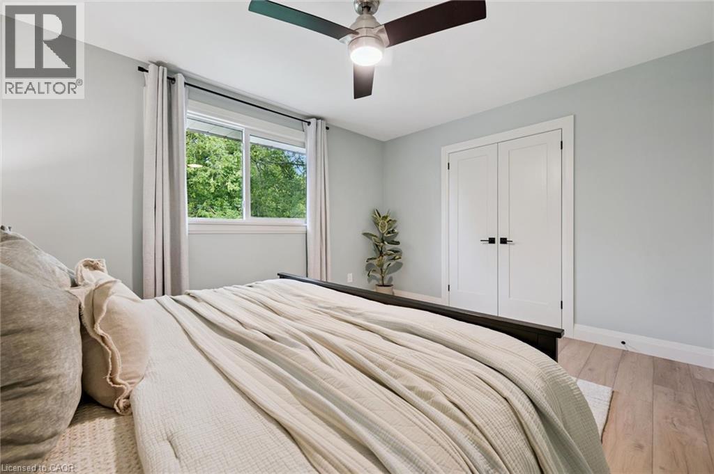 Wood-finish flooring, white double-panel doors with matte black hardware, and a ceiling fan with integrated lighting - 8 Christian Street, Baden, ON