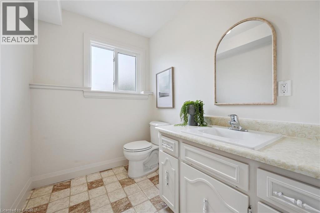 White vanity with integrated sink, chrome faucet, and arched mirror - 8 Christian Street, Baden, ON