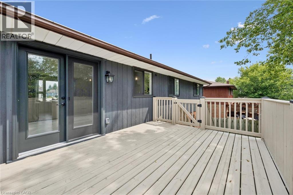Expansive outdoor deck with a light wood-finish surface, complete with a security gate and dark brown gutters - 8 Christian Street, Baden, ON