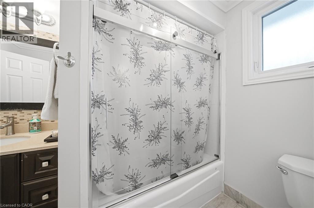Modern full bathroom featuring a sliding glass shower enclosure with decorative frosted patterning, white subway tile surround, and chrome fixtures - 6346 Neuchatel Road, Mississauga, ON