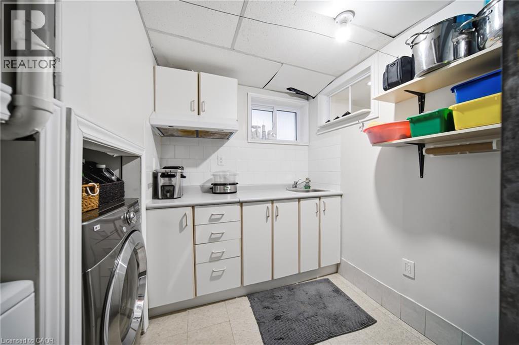 Dedicated laundry room featuring front-load washer, ample cabinetry with multiple drawers, stainless steel countertop, open shelving with organized storage bins, and practical layout designed for effi - 6346 Neuchatel Road, Mississauga, ON