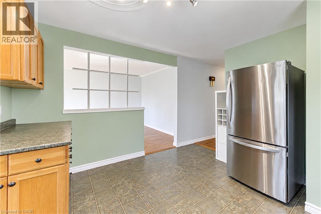 Kitchen featuring wood cabinetry, stone-finish countertops, and durable tile flooring - 64 Stanley Street, Cambridge, ON