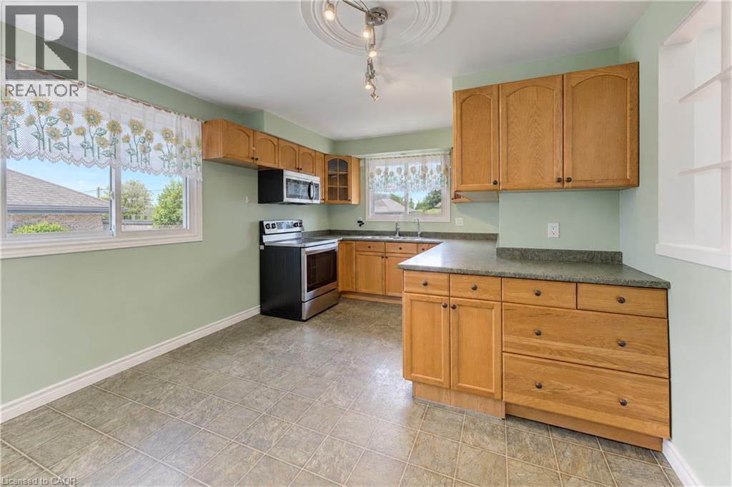 Kitchen featuring wood-finish cabinetry, stainless steel appliances, and a composite countertop - 64 Stanley Street, Cambridge, ON