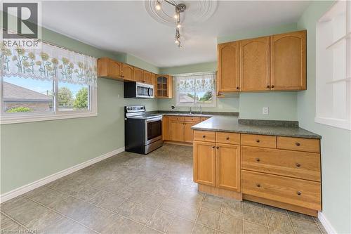 Kitchen featuring wood-finish cabinetry, stainless steel appliances, and a composite countertop - 64 Stanley Street, Cambridge, ON 