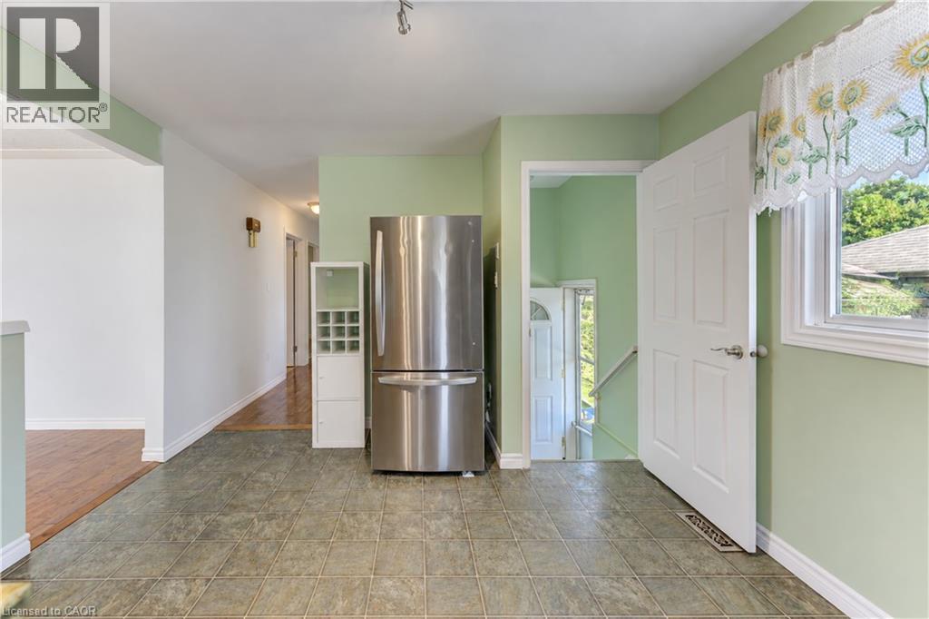 Tile flooring, stainless steel refrigerator, white interior doors, window with white trim, and light green wall paint - 64 Stanley Street, Cambridge, ON