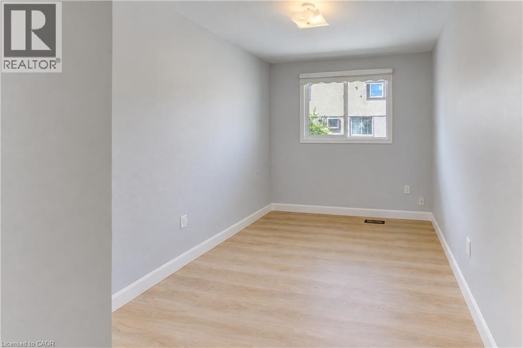 Light wood-finish flooring, white trim, and a window with a roller shade - 64 Stanley Street, Cambridge, ON